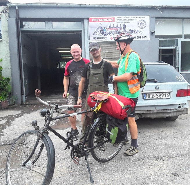 Im Vordergrund ein Fahrrad mit rotem Gep&auml;ck, dahinter Reinhard Klette mit zwei polnischen B&uuml;rgern. // &copy; Reinhard Klette