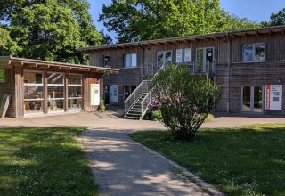 as Kreativzentrum ist das Herzst&uuml;ck unseres Campingplatzes. Der Geb&auml;udekomplex beherbergt unsere Kerzenzieherei, eine T&ouml;pferei, einen Yogaraum, die Spielbude, ein Fitnessstudio und eine Sauna auf zwei Etagen. Vor dem Geb&auml;ude befindet sich ein kleiner Platz mit viel Gr&uuml;nfl&auml;che auf dem wir gerne einige Feste veranstalten und auch unsere mobilen Hofl&auml;den Halt machen und regionale Produkte an unsere G&auml;ste verkaufen. // &copy; Carla Pommerehne / Campingplatz Seehof GmbH