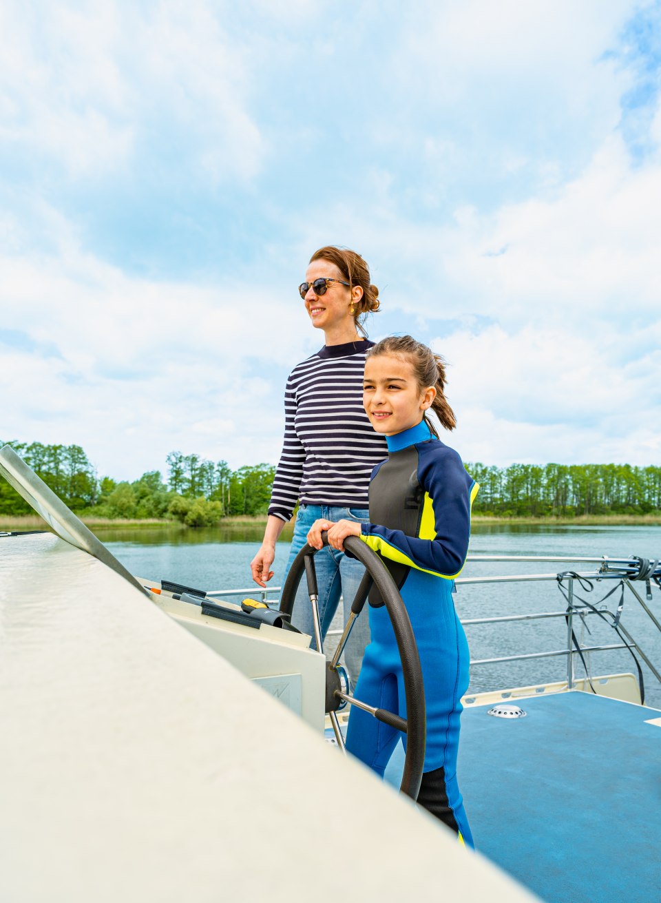 Eine Mutter mit Kind am Steuer von einem Hausboot // Die elfjährige Élodie traut sich, das große Schiff zu steuern. Mit Mama an ihrer Seite klappt das ganz wunderbar. // © MV-T/Tiemann Eine Mutter mit Kind am Steuer von einem Hausboot