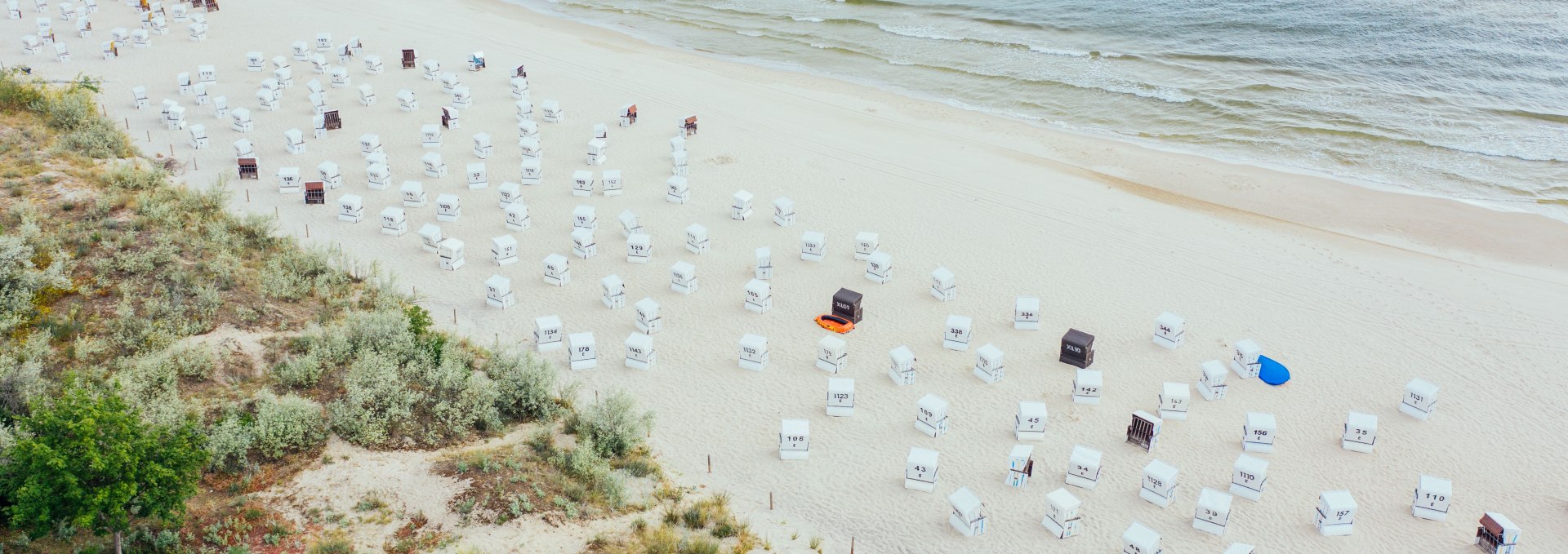 Luftaufnahme vom Strand in Heringsdorf mit zahlreichen weißen Strandkörben und ruhiger Ostsee im Hintergrund.