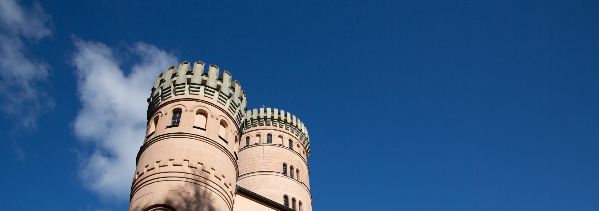 Jagdschloss Granitz auf Rügen mit runden Türmen und Zinnen vor blauem Himmel.