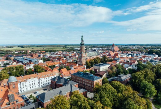 Die Silhouette von Greifswald aus der Luft und Blick auf die Kirchtürme, sowie Altstadt am Tage.
