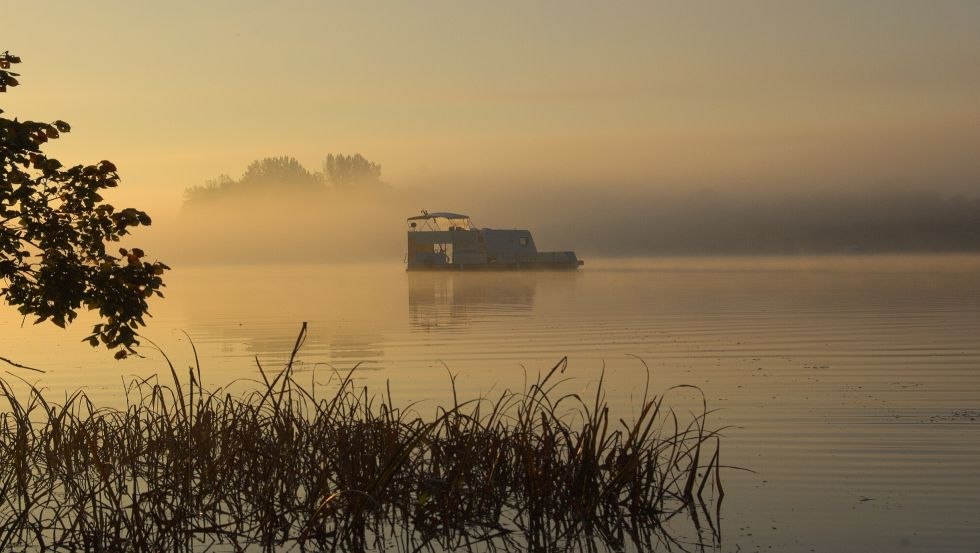 Sonnenaufgang auf dem See: mittendrin ein schwimmender Wohnwagen, © freecamper Sonnenaufgang auf dem See: mittendrin ein schwimmender Wohnwagen, © freecamper