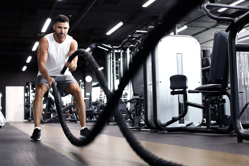 Athletic young man with battle rope doing exercise in functional training fitness gym., © FitAktiv Mirow