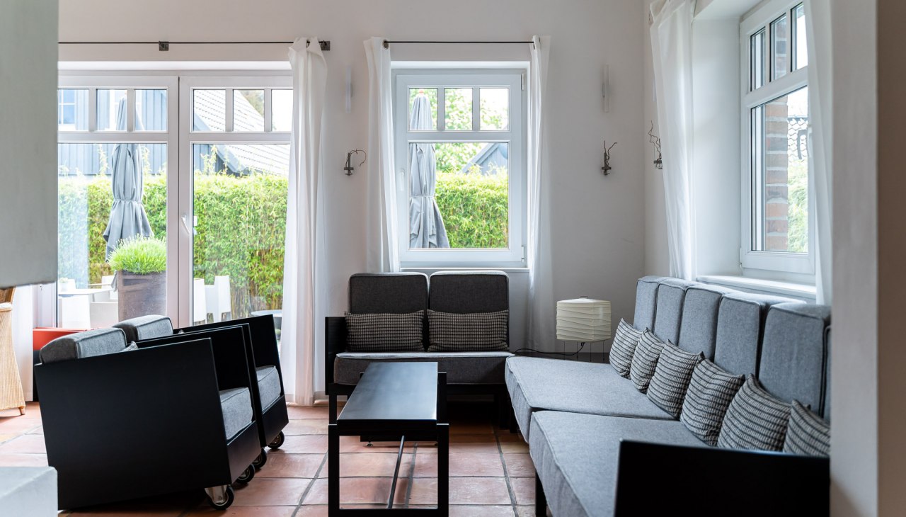 Ein heller und stilvoll eingerichteter Lounge-Bereich mit großen Fenstern, die viel Tageslicht hereinlassen. Graue Sofas und Sessel mit minimalistischen schwarzen Akzenten laden zum Entspannen ein. Die warmen Terrakotta-Böden und die schlichten weißen Vorhänge verleihen dem Raum eine entspannte und einladende Atmosphäre., © Hotel Carpe Diem Ein heller und stilvoll eingerichteter Lounge-Bereich mit großen Fenstern, die viel Tageslicht hereinlassen. Graue Sofas und Sessel mit minimalistischen schwarzen Akzenten laden zum Entspannen ein. Die warmen Terrakotta-Böden und die schlichten weißen Vorhänge verleihen dem Raum eine entspannte und einladende Atmosphäre., © Hotel Carpe Diem