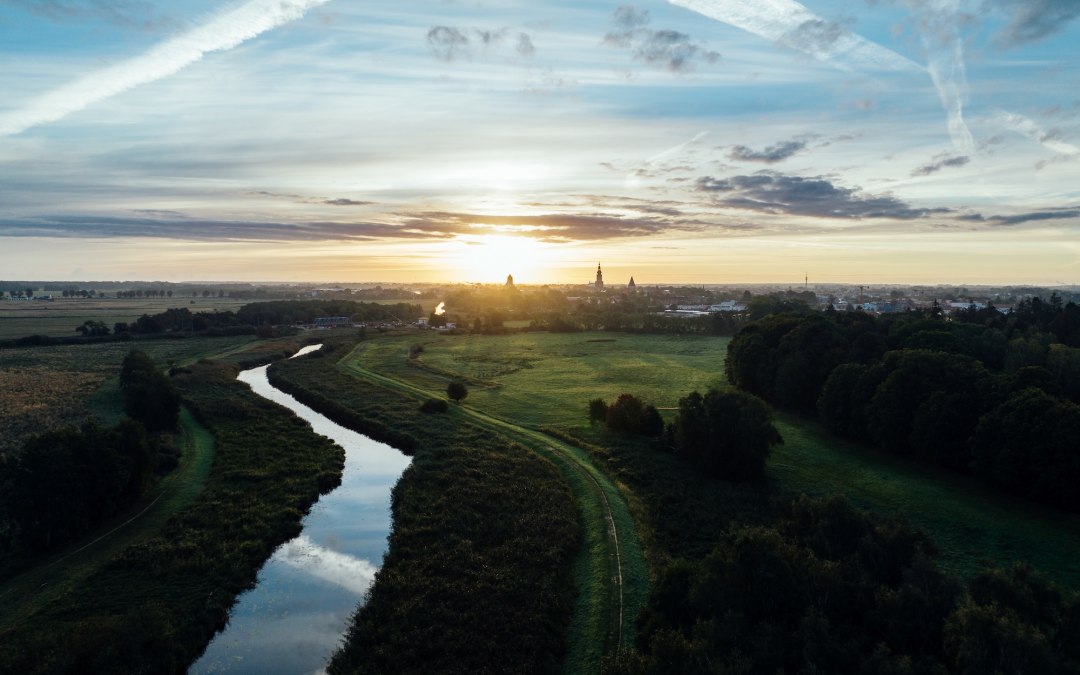 Sonnenaufgang über der Hansestadt Greifswald: Ein stiller Fluss schlängelt sich durch Wiesen, während Kirchtürme am Horizont langsam im Morgenlicht sichtbar werden. Mecklenburg-Vorpommern erwacht leise. // © MV-T/Gänsicke Sonnenaufgang über der Hansestadt Greifswald: Ein stiller Fluss schlängelt sich durch Wiesen, während Kirchtürme am Horizont langsam im Morgenlicht sichtbar werden. Mecklenburg-Vorpommern erwacht leise. // © MV-T/Gänsicke