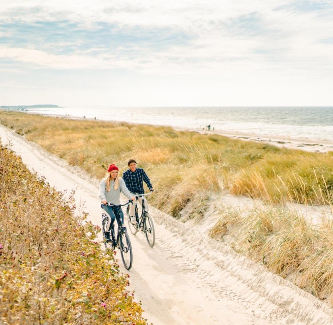 Eine gem&uuml;tliche Radtour entlang der malerischen D&uuml;nen auf der Insel Hiddensee, mit Blick auf die Ostsee im Hintergrund.