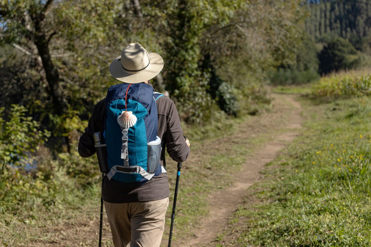 View from behind of a pilgrim walking on his way to Santiago de Compostela on a rural way. Way of saint james, Camino de Santiago // &copy; AdobeStock