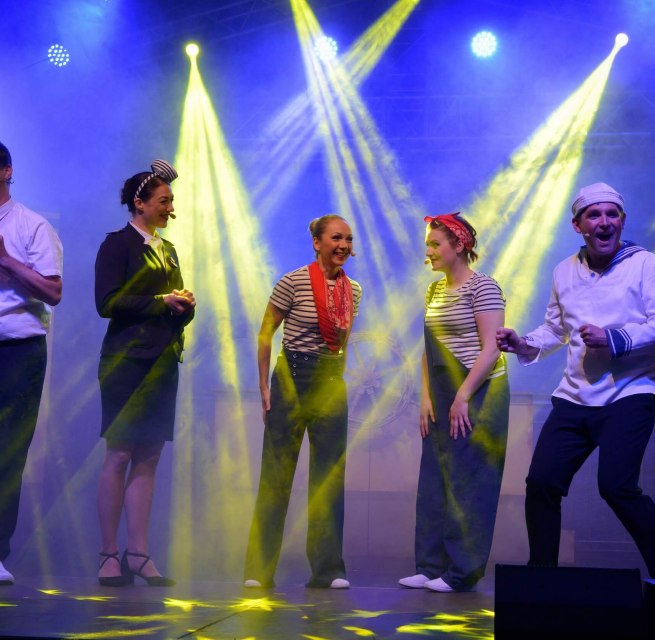 Acteurs in maritieme kostuums tijdens een cruiseshow op het podium van de Burgfestspiele Plau am See. // Spannend muziektheater op het openluchtpodium - het Plau am See Castle Festival neemt het publiek mee naar maritieme avonturen en de beste vakantiesfeer met een humoristische cruiseshow. // © Tourist Info Plau am See GmbH/Diedrichsen Acteurs in maritieme kostuums tijdens een cruiseshow op het podium van de Burgfestspiele Plau am See.