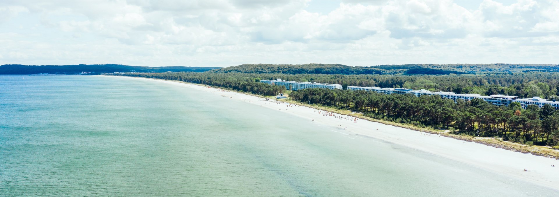 Luftfoto af de lange sandstrande ved Prora p&aring; R&uuml;gen med det historiske bygningskompleks og den tilst&oslash;dende kystskov.