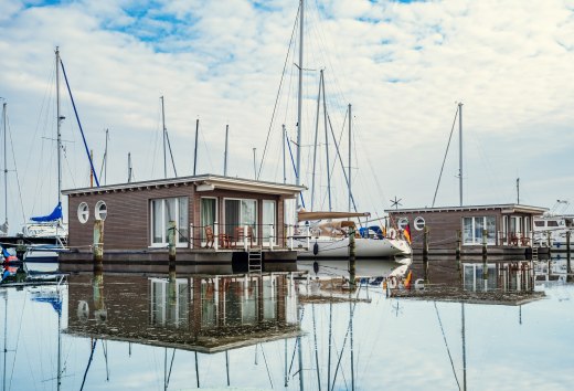 Hausboote und Segelboote liegen angeleint im Hafen von Krummin // Schwimmendes Urlaubsglück: Die im Stil von Hausbooten konstruierten Suiten sind fest verankert. // © MV-T/Tiemann Hausboote und Segelboote liegen angeleint im Hafen von Krummin