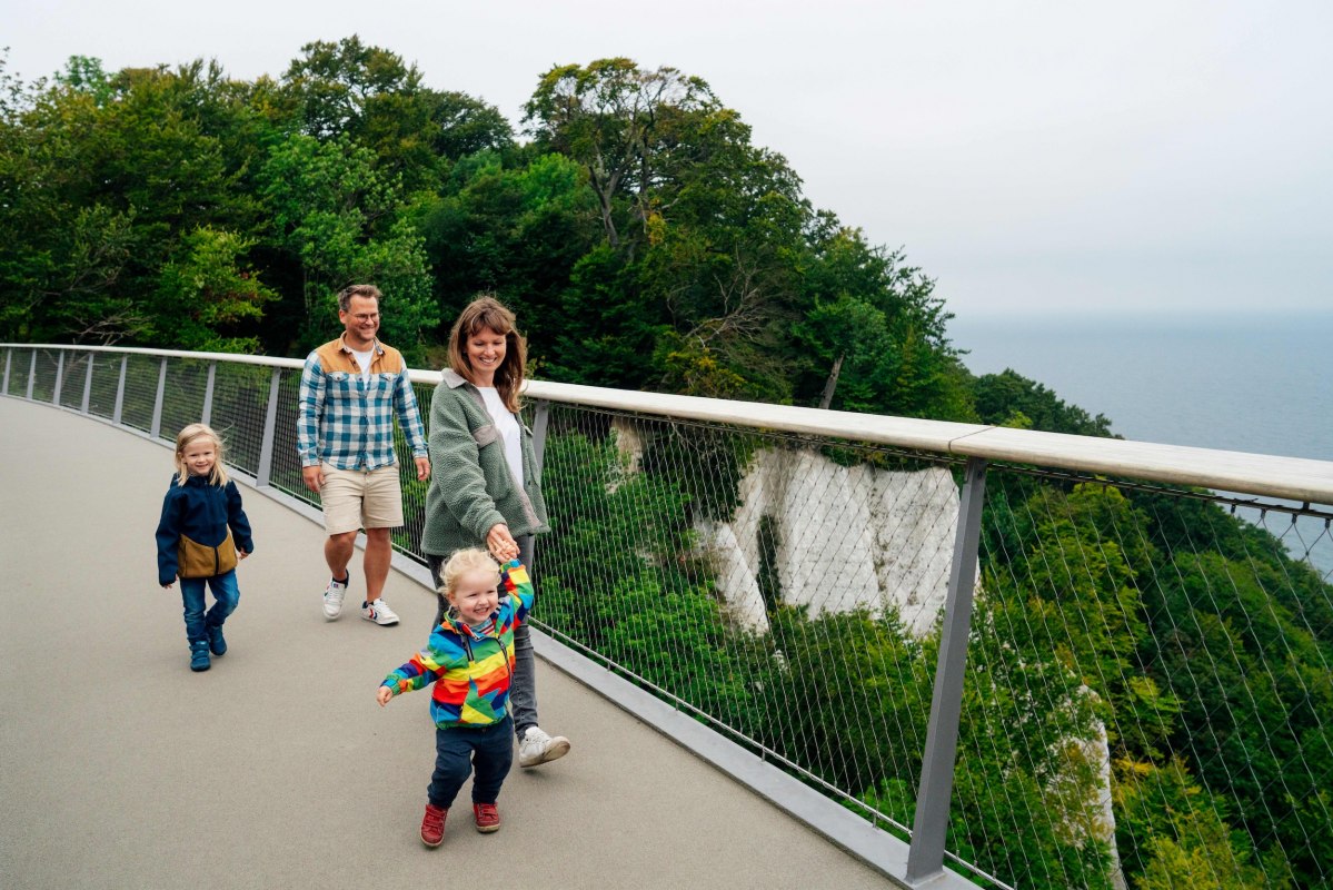 Mehrere Personen auf einer Aussichtsplattform mit Geländer, die einen weiten Blick über die grüne Landschaft genießen. // © Nationalpark-Zentrum KÖNIGSSTUHL / Dan Petermann Mehrere Personen auf einer Aussichtsplattform mit Geländer, die einen weiten Blick über die grüne Landschaft genießen. // © Nationalpark-Zentrum KÖNIGSSTUHL / Dan Petermann