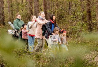 Kinder und Erwachsen genie&szlig;en gerade ein Waldbad. Sie gehen achtsam und mit geschlossenen Augen durch einen Wald. // &copy; Dominic Mann tiefen-blick.de