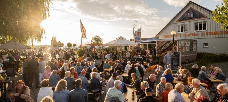 Live-Musik am Ribnitzer Fischhafen: volle B&auml;nke, Gespr&auml;che, Fischduft aus der R&auml;ucherei &ndash; Hafenflair bis in den Abend. // &copy; Ribnitzer Fischhafen / Hugo Scholz-Witzel