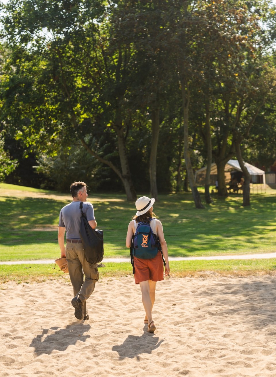 Een stel wandelt door een groen park in de richting van de Stolper F&auml;hrkrug, met een bord op de voorgrond.