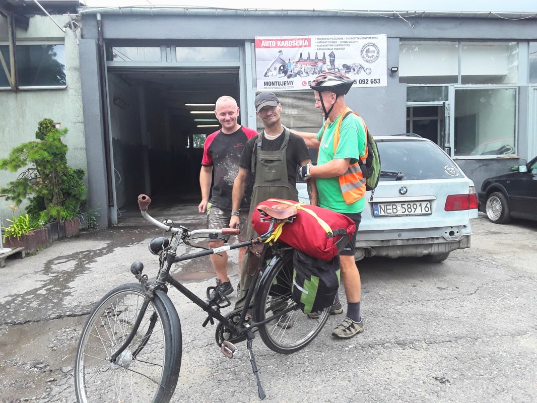 Op de voorgrond een fiets met rode bagage, daarachter Reinhard Klette met twee Poolse burgers. // &copy; Reinhard Klette