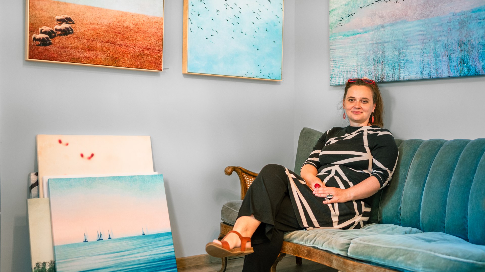 Claudia is ook een fotokunstenaar - ze zit op de bank met overal schilderijen om haar heen. // Ze bewerkt haar foto's zo dat het net abstracte schilderijen lijken. Waar kun je ze kopen? In haar galeriecafé, natuurlijk! // © MV-T/Tiemann Claudia is ook een fotokunstenaar - ze zit op de bank met overal schilderijen om haar heen.