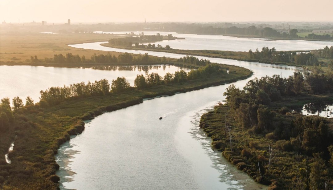 Ein Paar paddelt gemeinsam in einem Kanu &uuml;ber den Fluss die Peene in Mecklenburg-Vorpommern. Das Bild zeigt die Weite der Urlaubsregion Vorpommern.