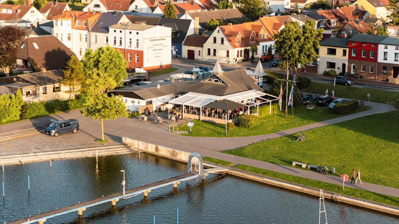 Restaurant DE ZEES in Ribnitz-Damgarten vanuit de lucht gezien &ndash; terras aan de oever, paden om er te komen en te vertoeven. // &copy; Ribnitzer Fischhafen/Hugo Scholz-Witzel