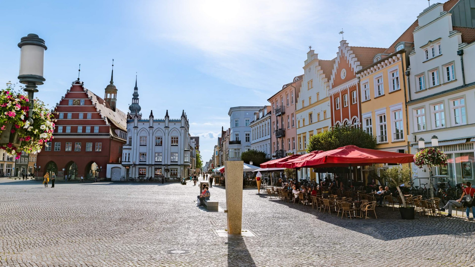 Marktplatz von Greifswald mit hanseatischen Gebäuden, Cafés und der Touristeninformation.