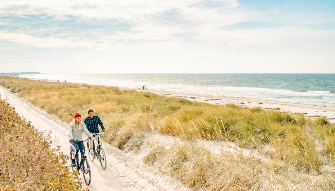 Eine gem&uuml;tliche Radtour entlang der malerischen D&uuml;nen auf der Insel Hiddensee, mit Blick auf die Ostsee im Hintergrund.