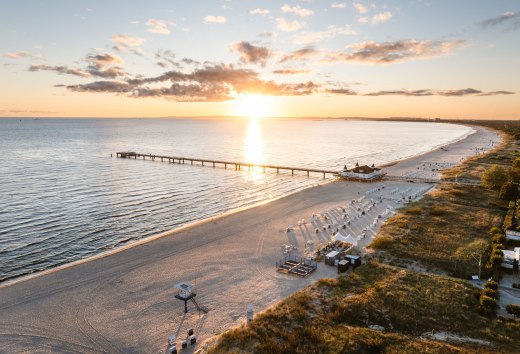 Luftaufnahme der Seebr&uuml;cke Ahlbeck bei Sonnenaufgang, Strand und Ostsee im goldenen Licht.