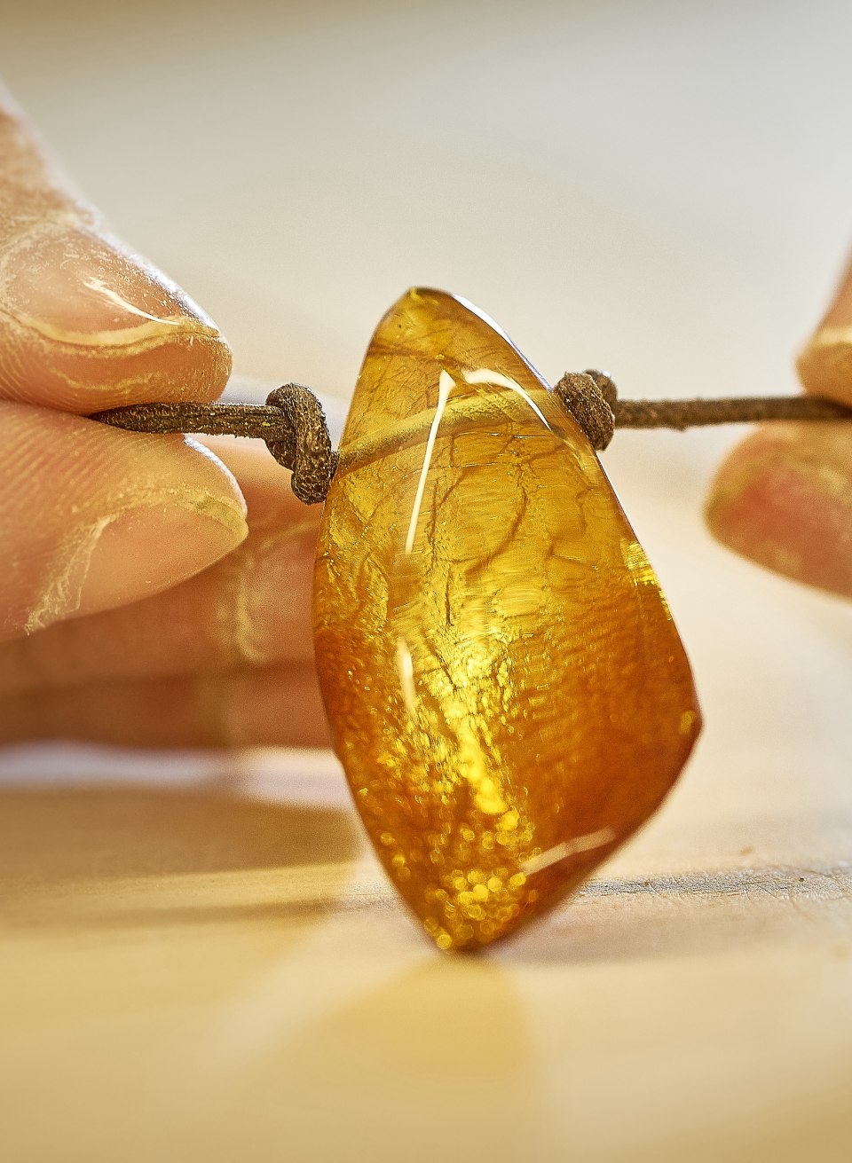 Hände schleifen ein goldgelbes Bernsteinstück im Deutschen Bernsteinmuseum Ribnitz-Damgarten. // Im Deutschen Bernsteinmuseum Ribnitz-Damgarten wird das alte Handwerk des Bernsteinschleifens lebendig. Hände formen goldenes Ostseegold zu funkelnden Schmuckstücken – ein Erlebnis, das die jahrhundertealte Tradition der Bernsteinverarbeitung an der Ostseeküste spürbar macht. // © MV-T/Pocha.de Hände schleifen ein goldgelbes Bernsteinstück im Deutschen Bernsteinmuseum Ribnitz-Damgarten.
