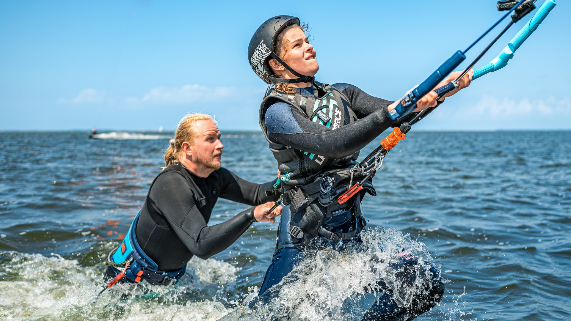 Der Kite zieht Luisa aus dem Wasser. Der Kitelehrer h&auml;lt sie sicher hinten fest.