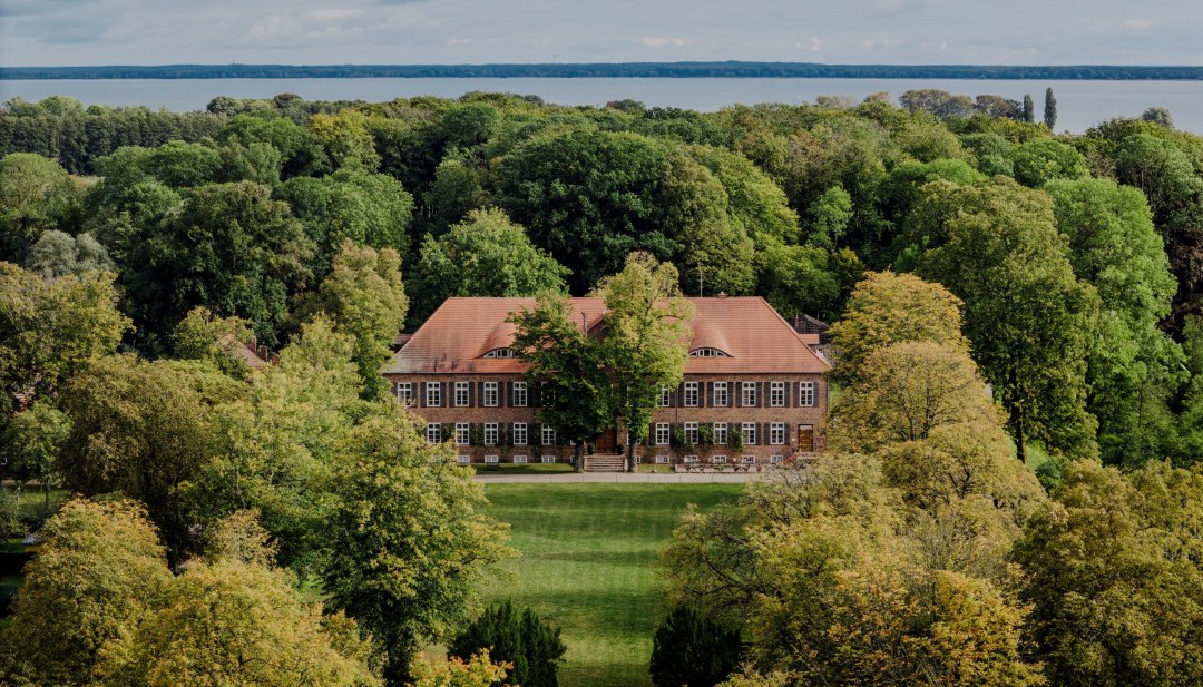 Historisch landhuis Ludorf in een park met bomen en uitzicht op het meer in Mecklenburg-Vorpommern.