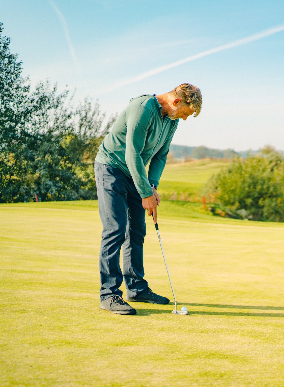 Golfspieler beim Putten auf dem Grün im Ostsee-Golf-Resort Wittenbeck mit Blick auf Landschaft. // Das Ostsee-Golf-Resort Wittenbeck verbindet sportliche Aktivität mit weiter Landschaft. Zwischen saftigem Grün und Wasserflächen konzentriert sich der Blick auf das Wesentliche – ein Ort, an dem Golfen zur achtsamen Auszeit wird. // © MV-T/Petermann Golfspieler beim Putten auf dem Grün im Ostsee-Golf-Resort Wittenbeck mit Blick auf Landschaft.