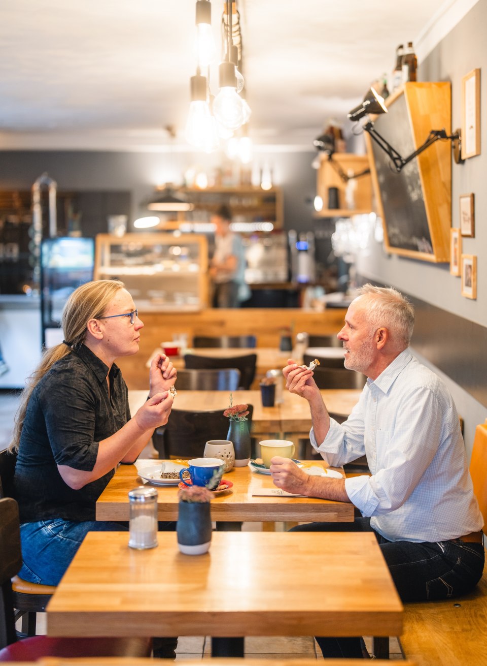Genussvoller Nachmittag – Kaffee und Kuchen charmanten Café Medewege in Mecklenburg-Vorpommern., © TMV/Gross Zwei Personen genießen Kaffee und Kuchen in einem gemütlichen Café mit moderner Einrichtung.