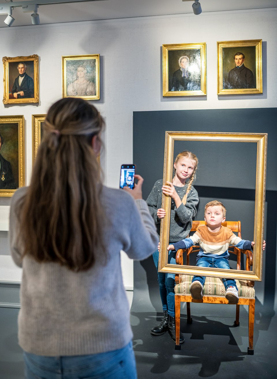 de nakomeling lacht vriendelijk vanuit een gouden fotolijstje - voor het portret in olie, sorry: souvenirfoto // &copy; MV-T/Tiemann