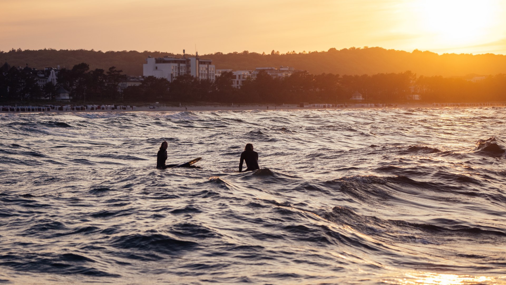 Zwei Surfer auf der Ostsee bei Binz während eines stimmungsvollen Sonnenuntergangs.