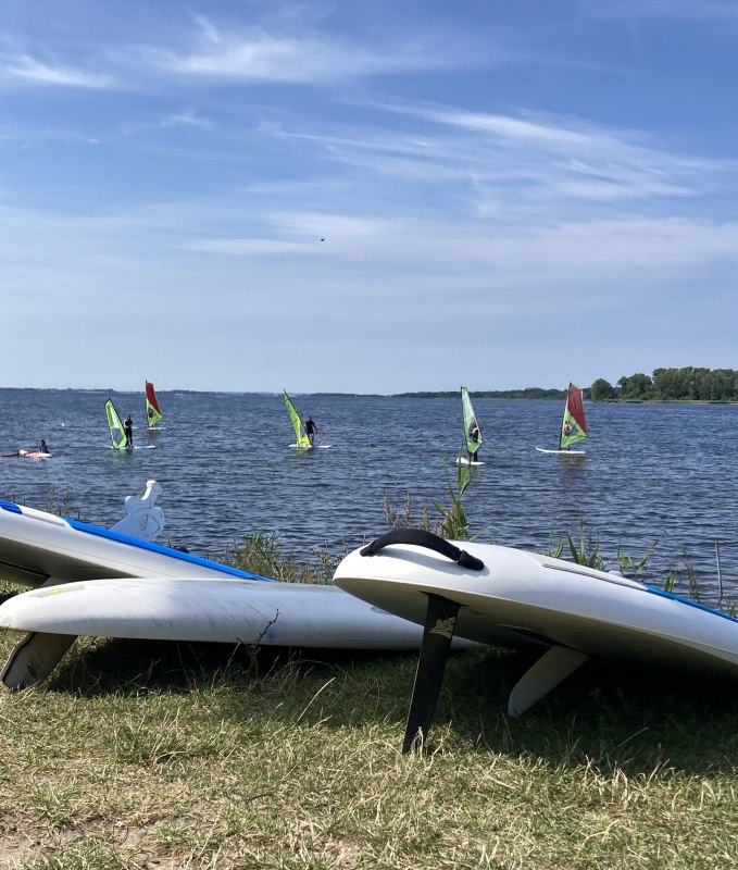 Sommerliche Stimmung am Salzhaff in Rerik: Windsurf Grundkurs und Verleih in entspannter Atmosphäre. Flaches Wasser, Natur und viel Platz bieten ideale Bedingungen für Anfänger und sorgen für ein unvergessliches Wassersporterlebnis an der Ostsee. // © Henning Schult Sommerliche Stimmung am Salzhaff in Rerik: Windsurf Grundkurs und Verleih in entspannter Atmosphäre. Flaches Wasser, Natur und viel Platz bieten ideale Bedingungen für Anfänger und sorgen für ein unvergessliches Wassersporterlebnis an der Ostsee. // © Henning Schult