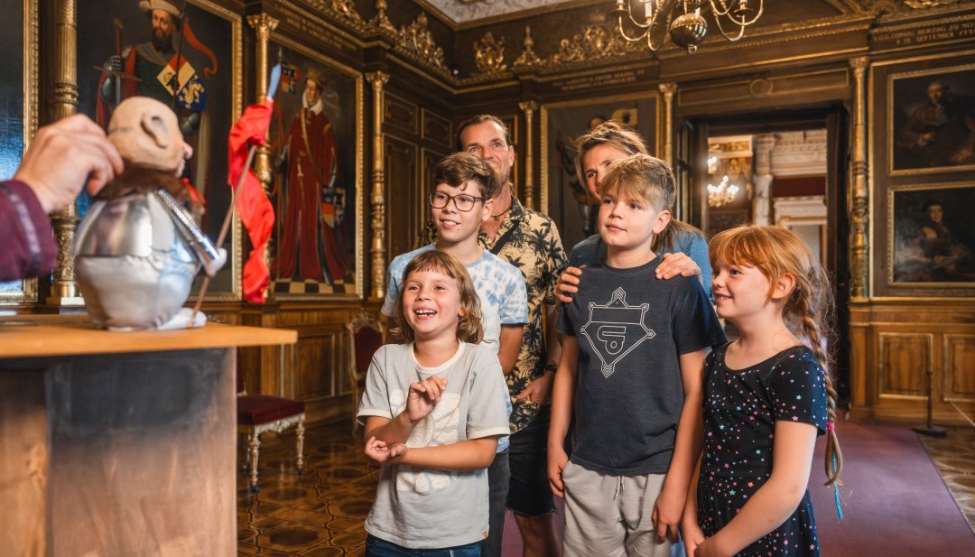 Een gezin bekijkt een interactieve poppenkastrondleiding door het kasteel van Schwerin.