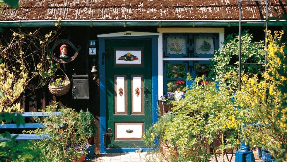 Bont kleuren en met prachtig houtsnijwerk, een huisdeur van een vissershuisje op het Fischland-Dar&szlig;-Zingst // &copy; MV-T/Legrand