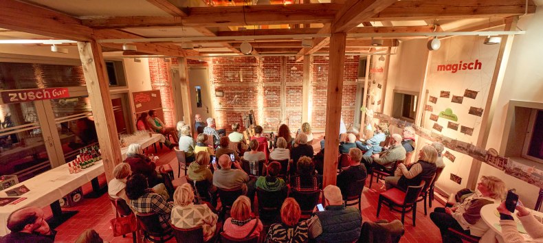 Menschen sitzen in der beleuchteten Remise und schauen zur Bühne // © Oliver Borchert Menschen sitzen in der beleuchteten Remise und schauen zur Bühne // © Oliver Borchert