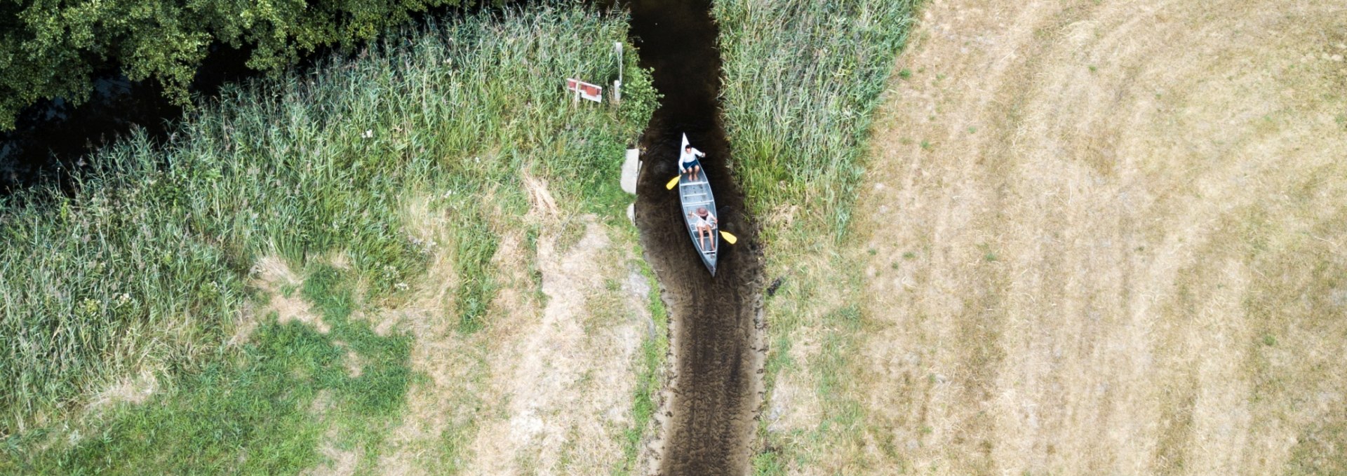 Ein Kanu auf einem Kanal, der fast kein Wassr mehr hat aus der Luft.