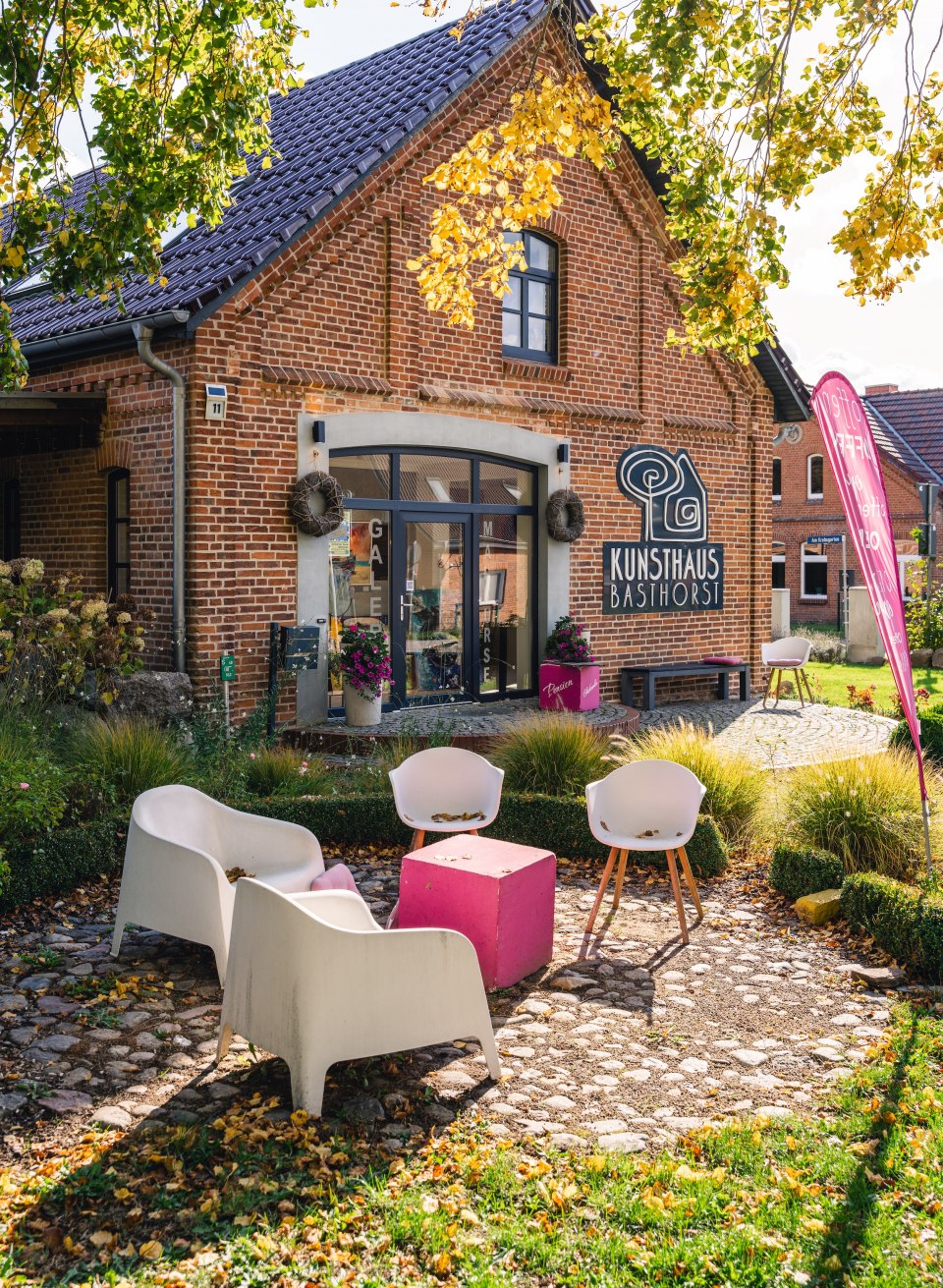 Das Kunsthaus Basthorst in einem herbstlichen Garten, umgeben von gelben und grünen Blättern, mit Sitzgelegenheiten im Außenbereich. // Kunst und Kreativität erleben – Das Kunsthaus Basthorst lädt zum Entdecken ein. // © MV-T/Gross Das Kunsthaus Basthorst in einem herbstlichen Garten, umgeben von gelben und grünen Blättern, mit Sitzgelegenheiten im Außenbereich.