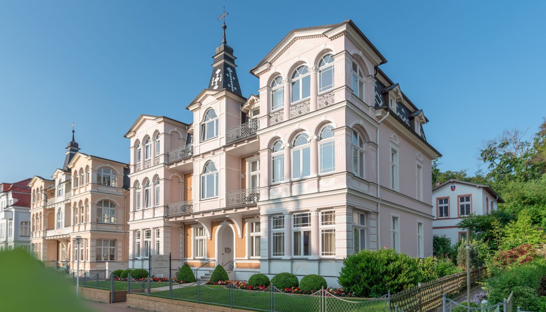 Historische B&auml;dervilla in Ahlbeck auf Usedom mit verzierten Balkonen und T&uuml;rmchen bei strahlend blauem Himmel.