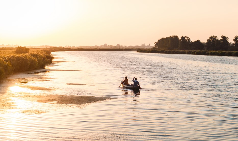 Ein ruhiger Abend auf dem Wasser: Zwei Personen paddeln bei Sonnenuntergang durch die weiten Gew&auml;sser Vorpommerns, umgeben von Natur und Stille.