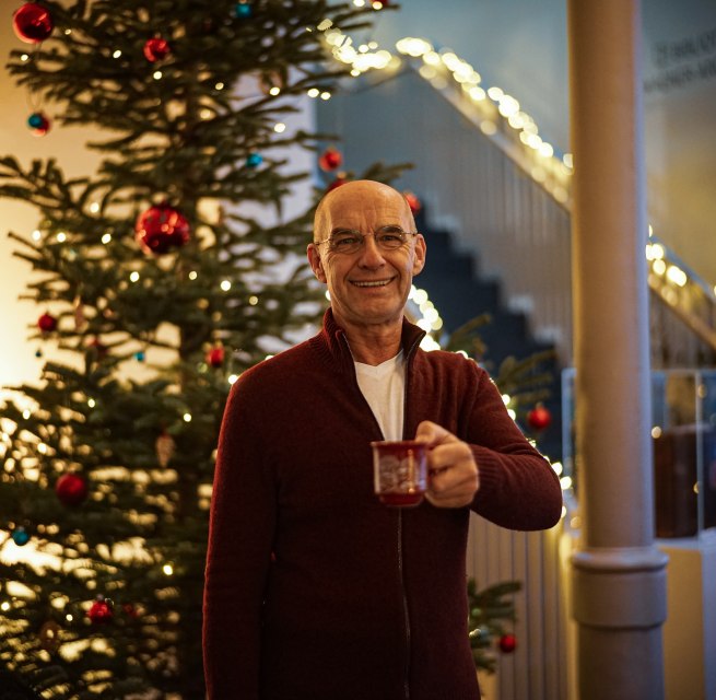 Chrtistoph Prinz mit einer Tasse Punsch vor dem Weihnachtsbaum im Kulturquartier, © Kulturquartier, Erik Swiatloch