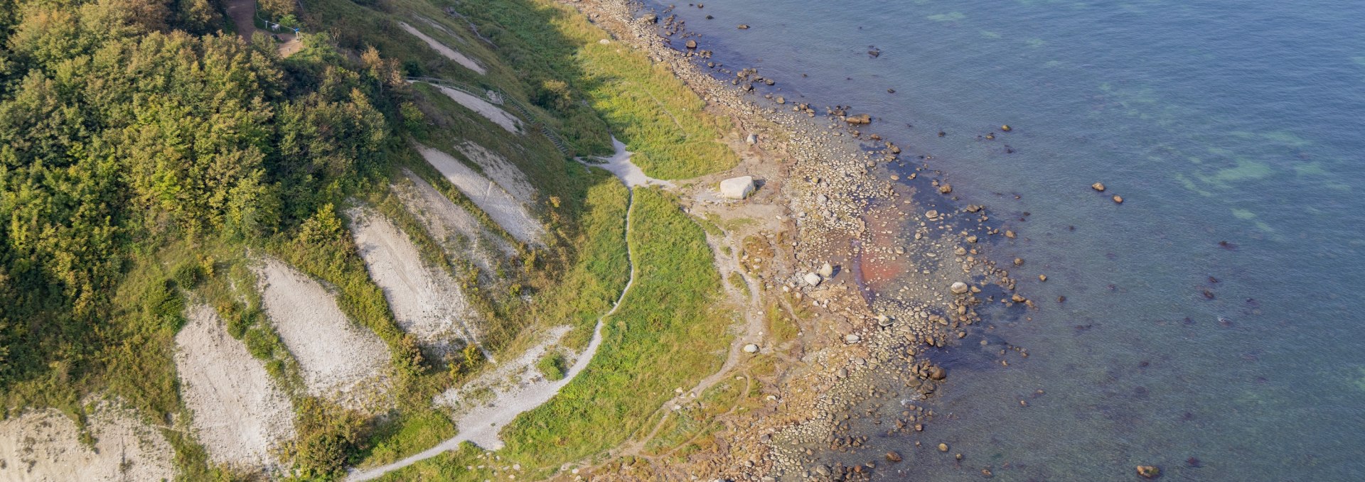 Luftaufnahme der K&uuml;ste am Kap Arkona mit steilen Kreidefelsen, gr&uuml;ner Vegetation und klarem Ostseewasser.
