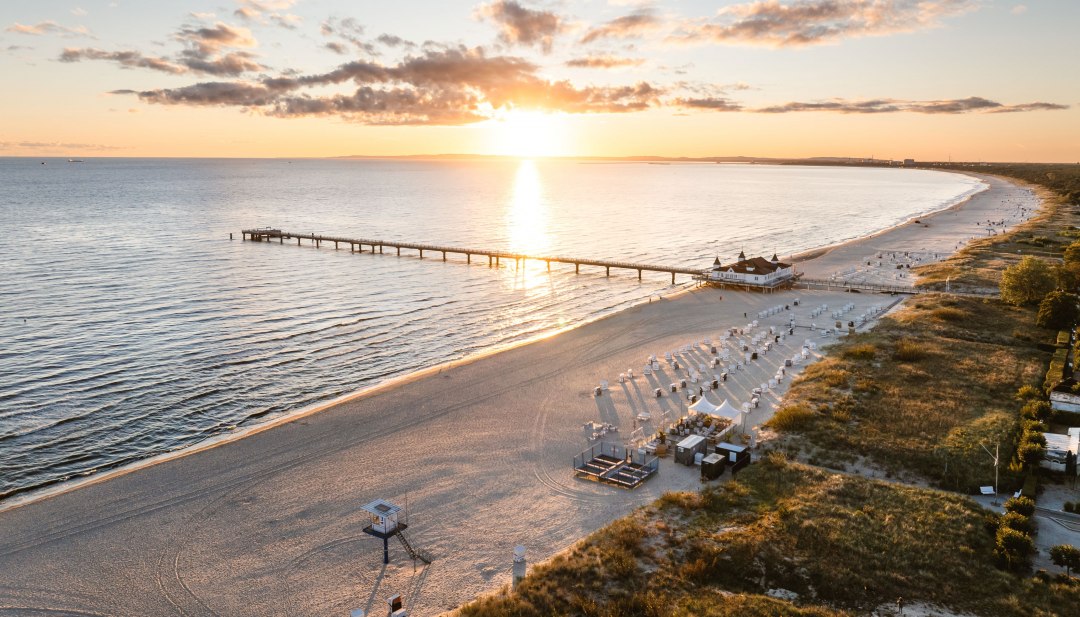 Luftfoto af Ahlbeck-molen ved solopgang, stranden og Østersøen i gyldent lys. // Solopgang over Østersøen, Ahlbecks mole strækker sig ud mod lyset – en kulisse for et bryllup med udsigt. // © MV-T/Gross Luftfoto af Ahlbeck-molen ved solopgang, stranden og Østersøen i gyldent lys.