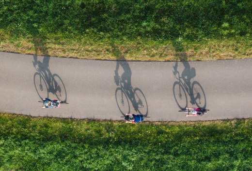 Drei Radfahrer auf einer Gravelbike-Tour durch das Peenetal bei Dargun, umgeben von saftigem Gr&uuml;n und strahlendem Sonnenschein.