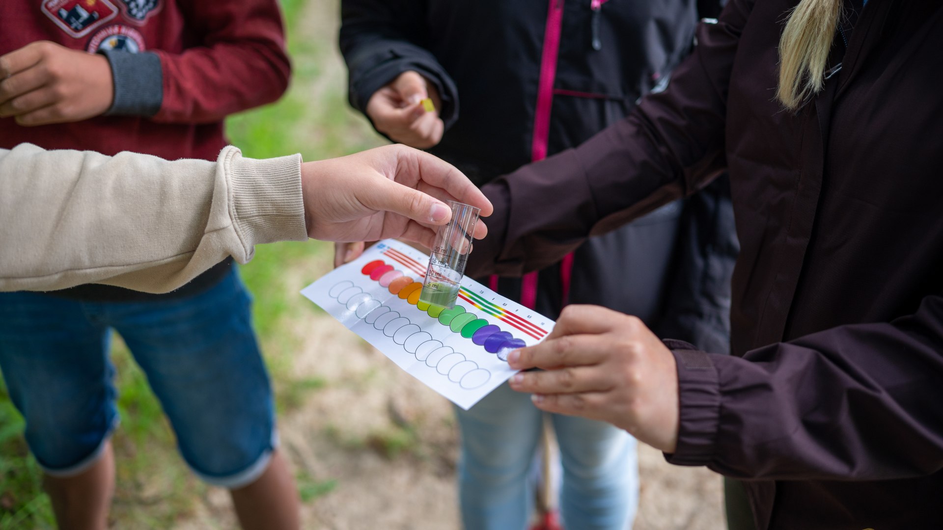 Meeresbiologin mit Sch&uuml;lerin untersuchen mit Farbtabelle den PH-Wert.
