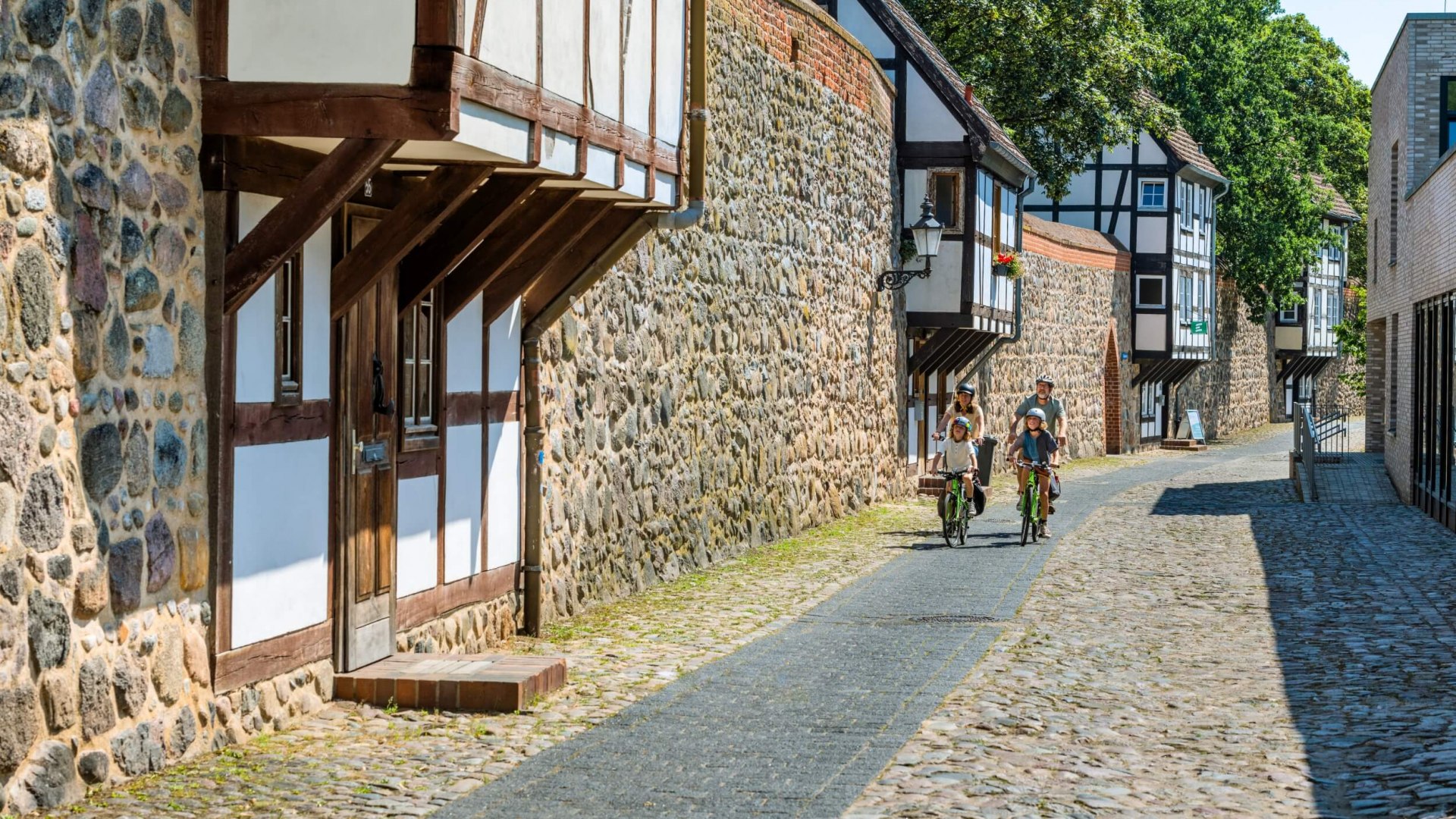Eine Familie fährt vorbei an der Wehranlage Neubrandenburgs. Diese ist aus Naturstein und Fachwerk. // Jede Menge Naturstein und Fachwerk: Die Neubrandenburger Wehranlage ist ein Meisterstück gotischer Baukunst // © MV-T/Tiemann Eine Familie fährt vorbei an der Wehranlage Neubrandenburgs. Diese ist aus Naturstein und Fachwerk.