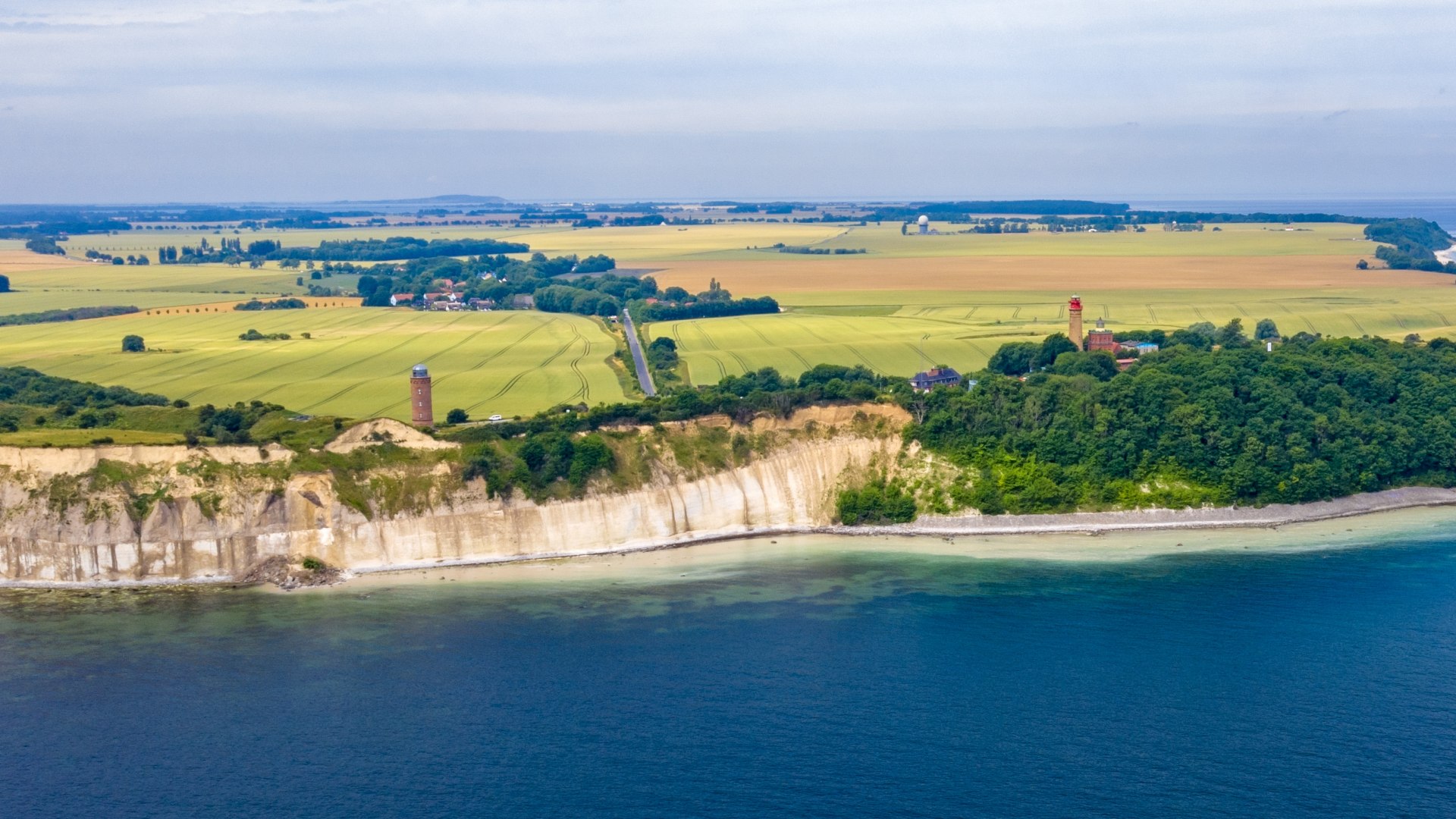 Luftaufnahme der Kreidefelsen am Kap Arkona auf der Insel R&uuml;gen. Im Hintergrund erstrecken sich Felder und die Ostsee unter einem klaren Himmel.