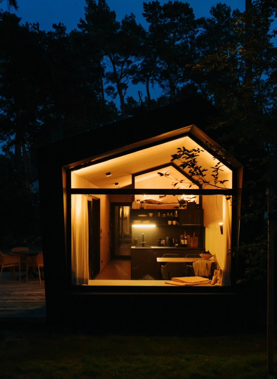 Natur trifft Design – stilvolles Tiny House mitten im Wald für eine entspannte Auszeit mit Komfort und Ruhe., © Cabin28 Gemütlich beleuchtetes Tiny House bei Nacht, mit Blick in den stilvoll eingerichteten Wohnbereich, umgeben von Natur.