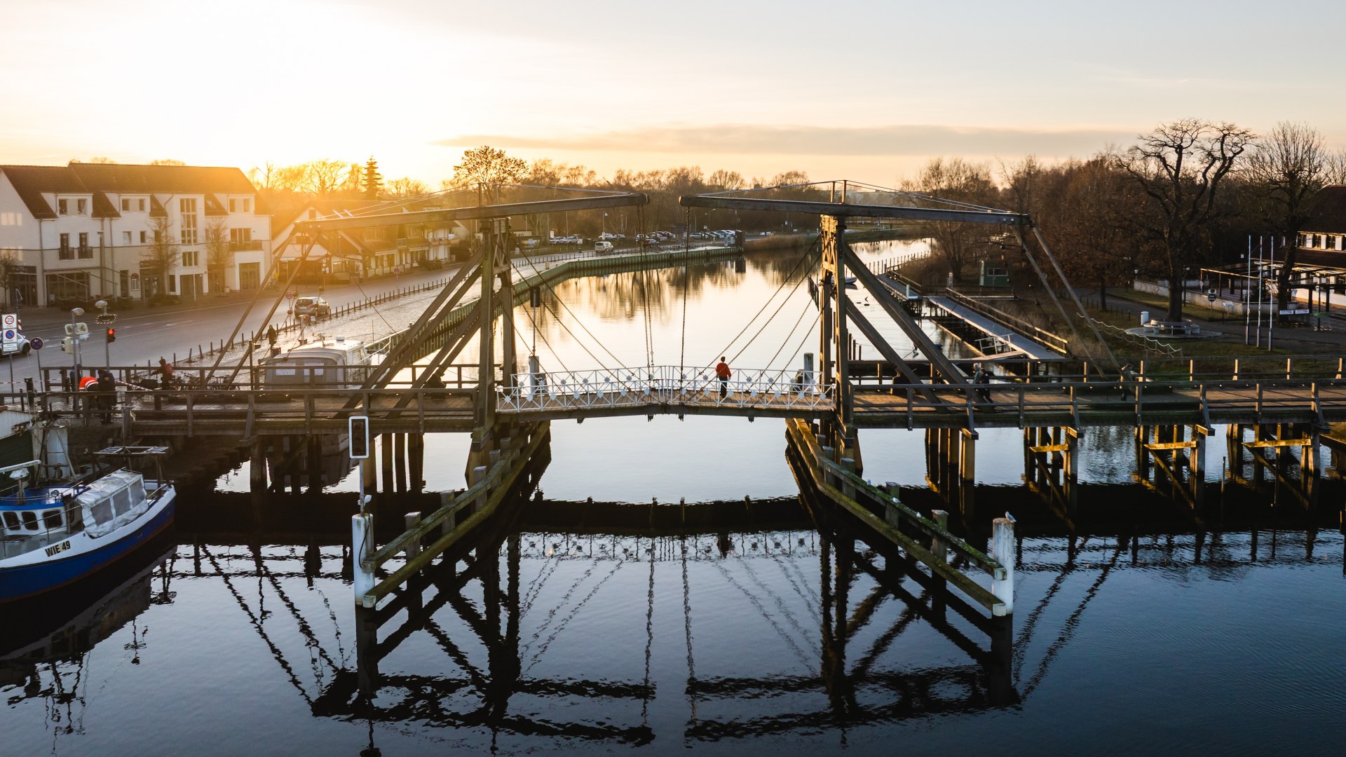 Historische Wiecker Klappbrücke bei Greifswald im goldenen Sonnenuntergangslicht über dem Wasser. // Die Wiecker Klappbrücke bei Greifswald taucht im Abendlicht in goldene Farben. Seit über 100 Jahren verbindet das historische Wahrzeichen die Ufer und öffnet sich für Segelboote auf dem Weg zur Ostsee. Ein Moment, der die maritime Seele Vorpommerns spürbar macht. // © MV-T/Gross Historische Wiecker Klappbrücke bei Greifswald im goldenen Sonnenuntergangslicht über dem Wasser.